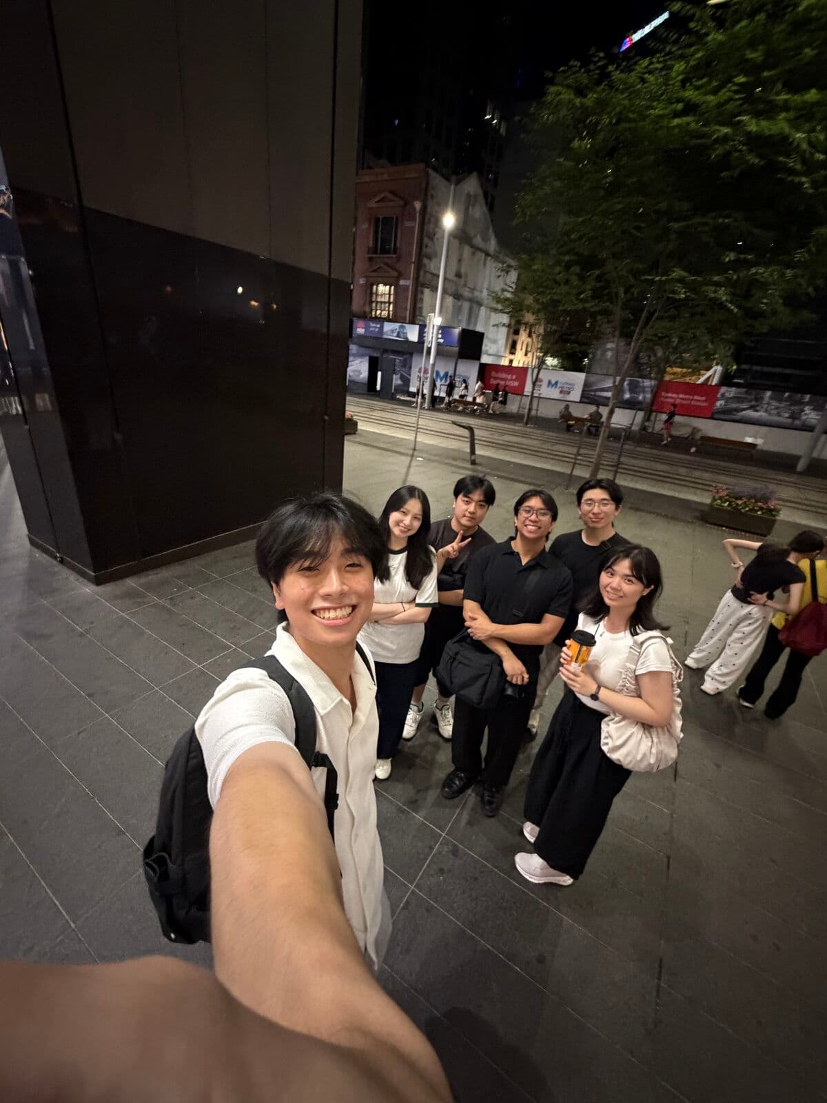 Eric taking a selfie with a group of friends on a city street at night