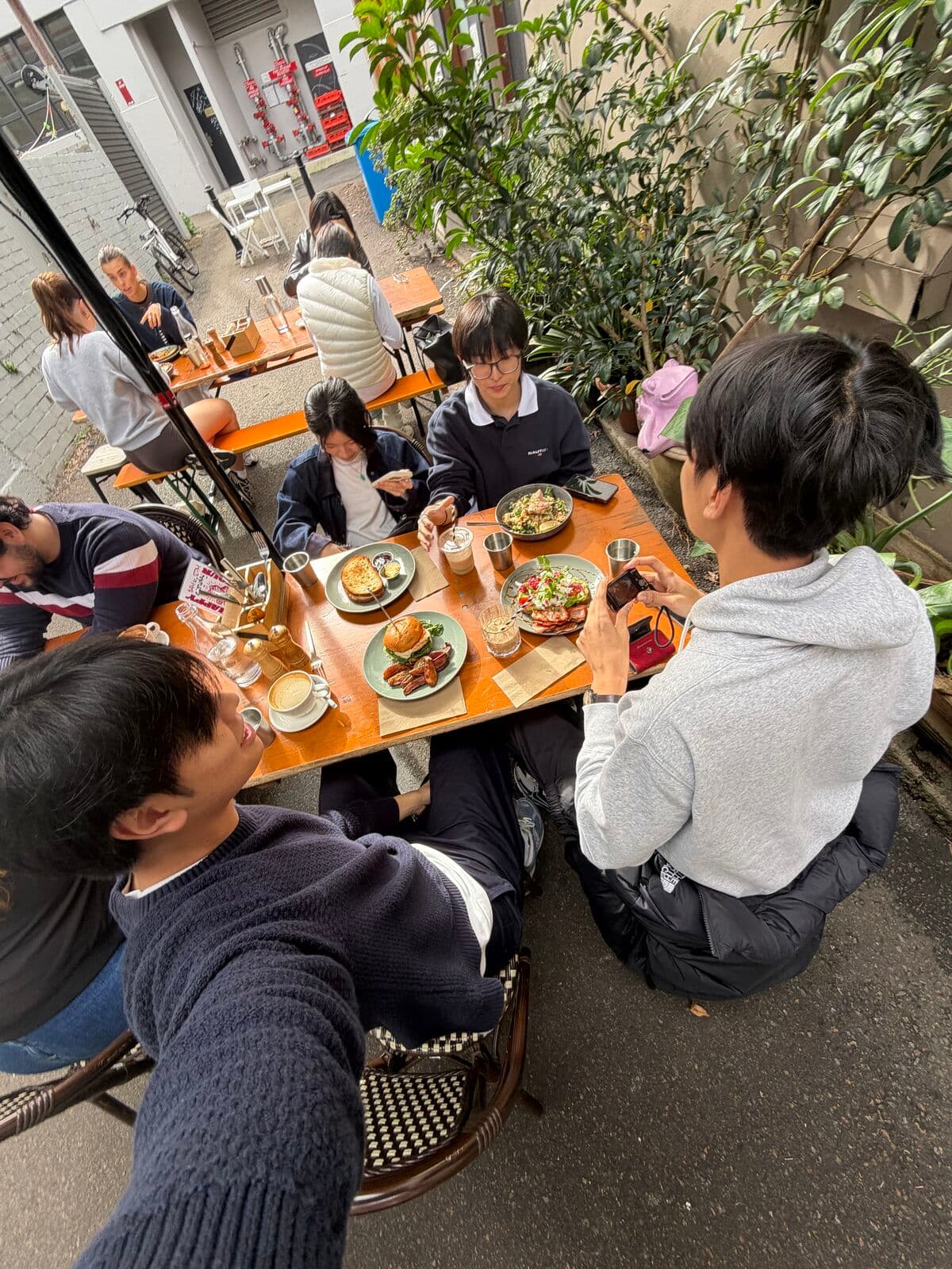 A selfie over brunch with friends at an outdoor table among plants