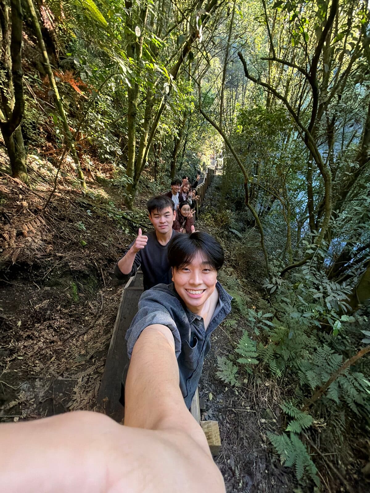 Eric taking a selfie on a narrow bush track, with friends following behind